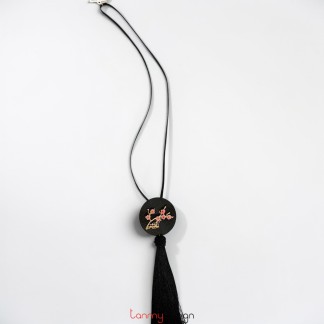 Black round metal pendant necklace with flower detail and black tassels