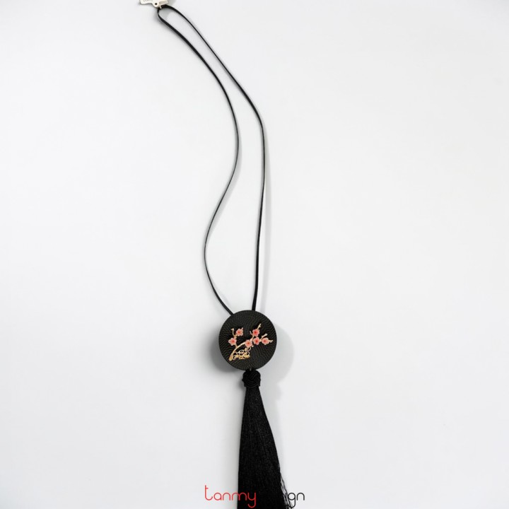 Black round metal pendant necklace with flower detail and black tassels